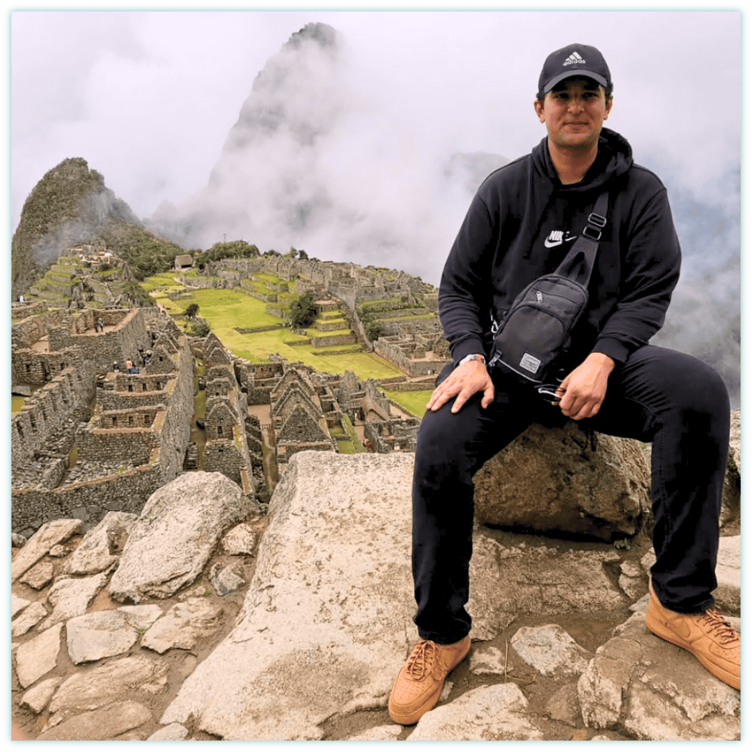 Yacin bij Machu Picchu, zittend met uitzicht op de historische Inca-ruïnes en de omliggende groene bergen in Peru