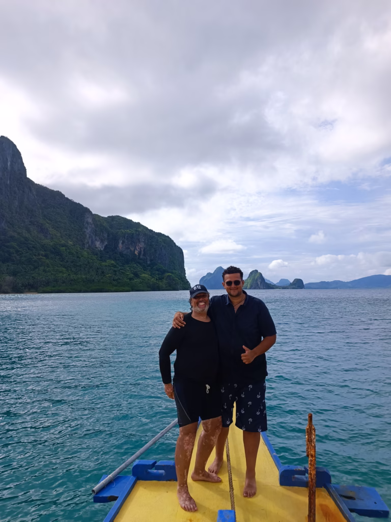 Vader en zoon genieten van een boottocht in El Nido, Filipijnen, omringd door helderblauw water en indrukwekkende rotsformaties.